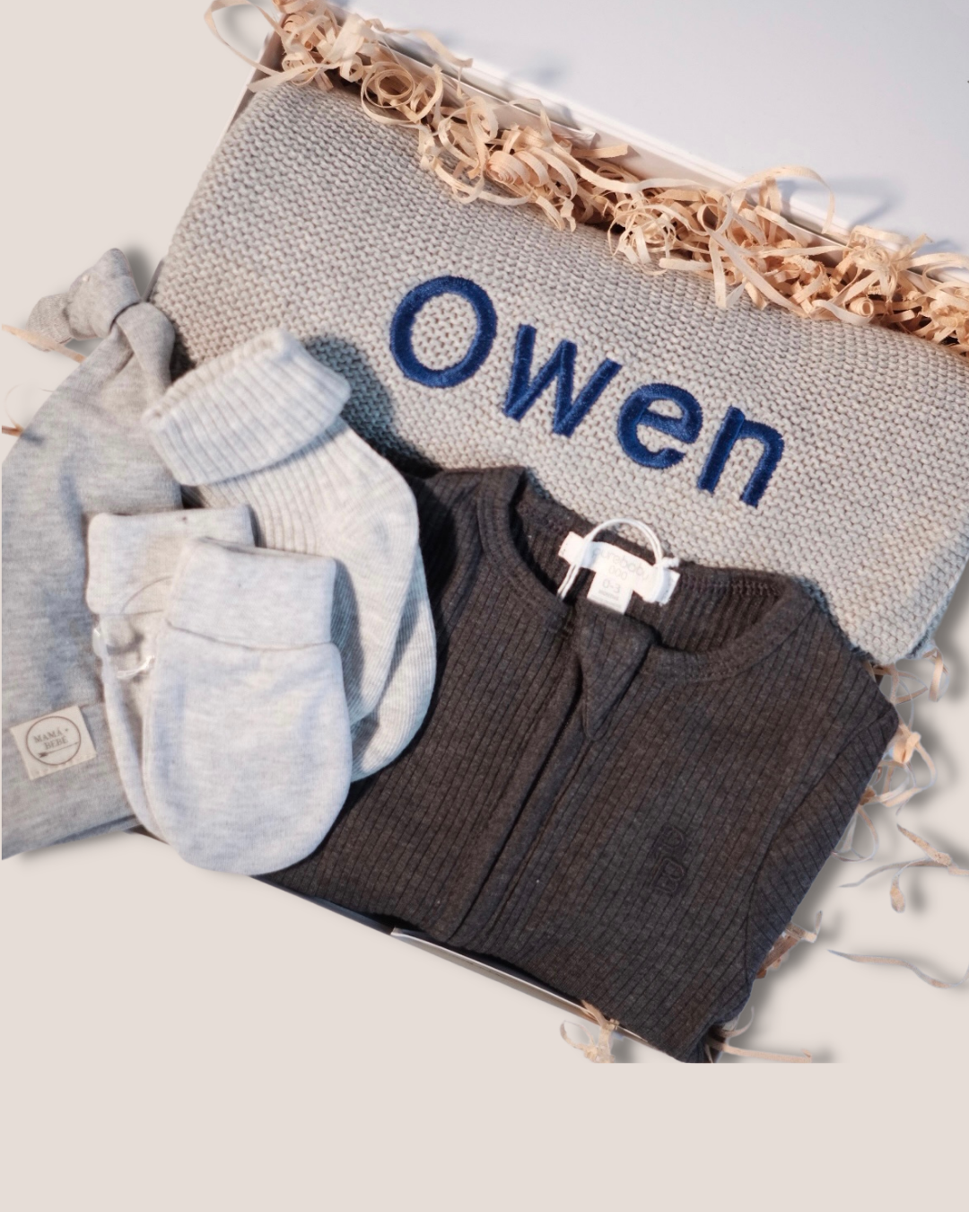 colour:charcoal | Close-up of charcoal welcome baby gift box with personalised OWEN knit blanket
